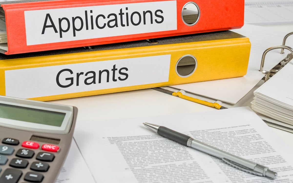 Binders labeled Applications and Grants beside forms and a calculator